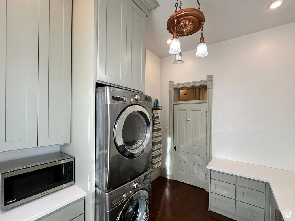 Washroom with recessed lighting, stacked washer and dryer, dark wood-style floors, and laundry area
