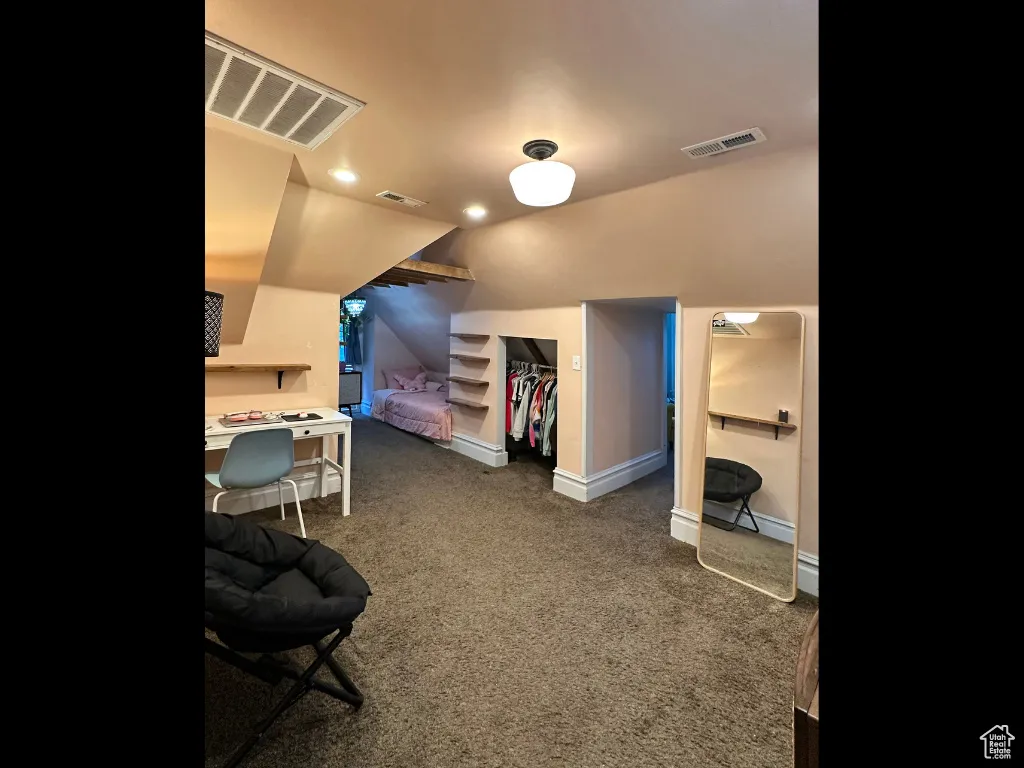 Carpeted bedroom featuring vaulted ceiling, baseboards, and visible vents