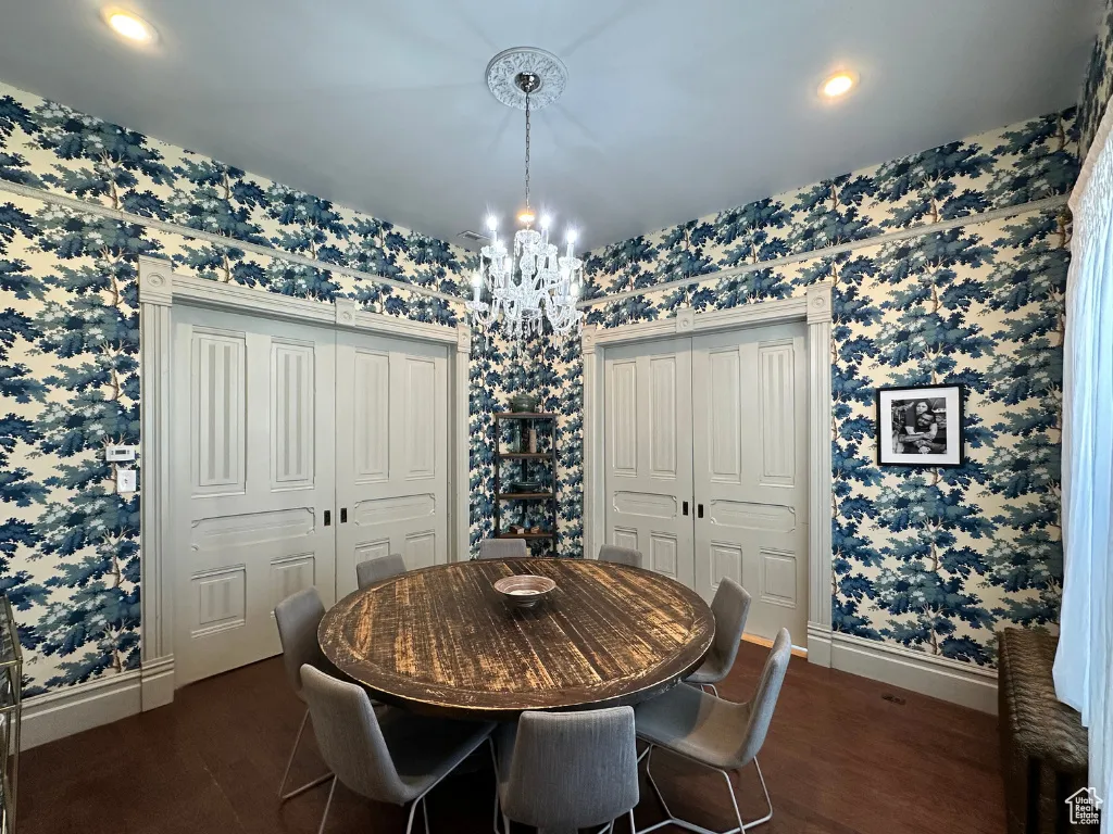 Dining area featuring wallpapered walls, baseboards, and a chandelier