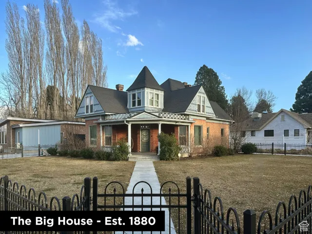 Victorian home featuring a front lawn, a gate, brick siding, and a fenced front yard
