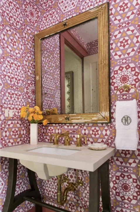 Bathroom featuring wallpapered walls and a sink