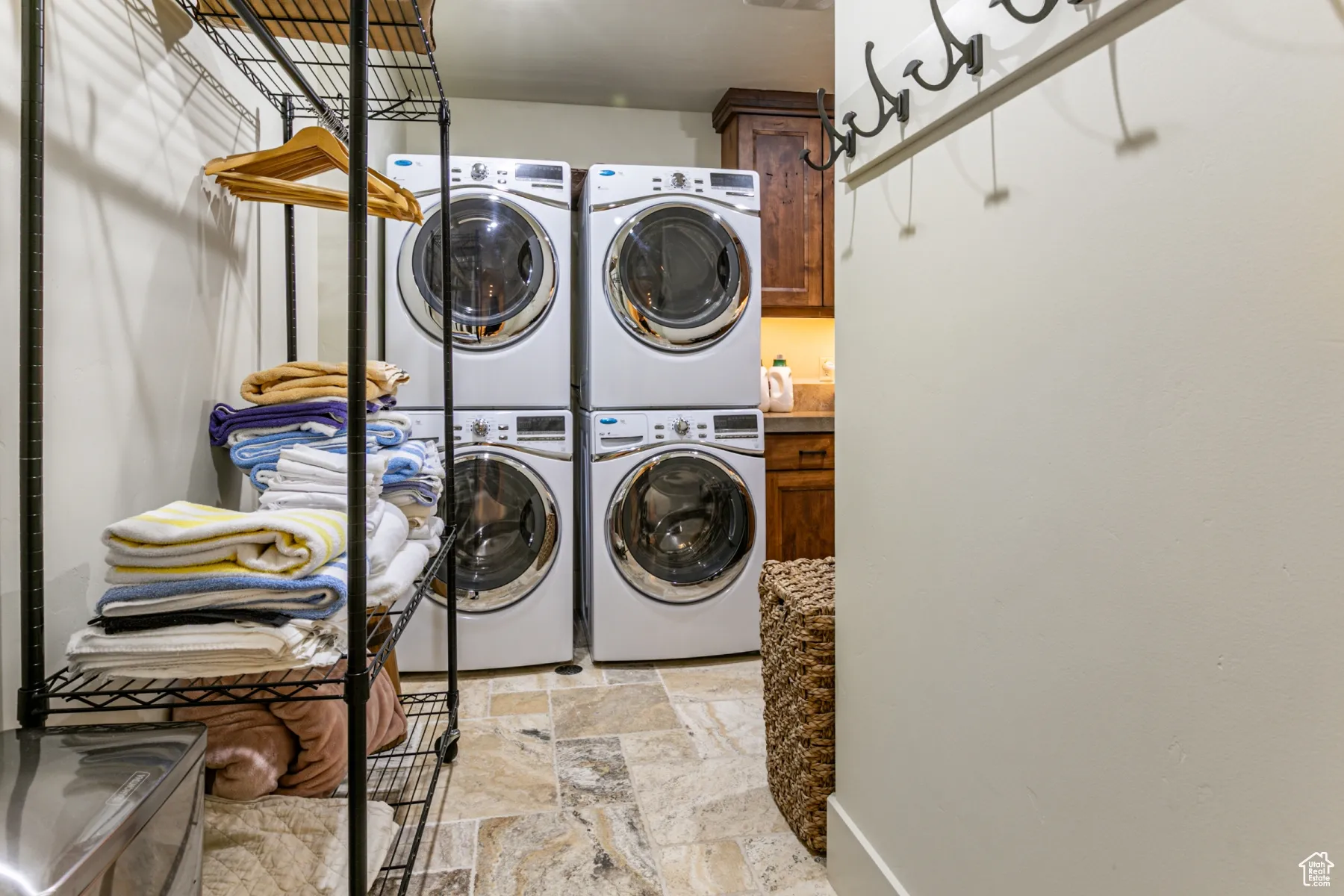 Washroom with stone tile flooring, cabinet space, stacked washing maching and dryer, and washing machine and clothes dryer