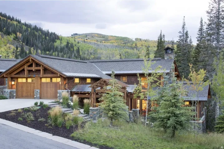 View of front of property with a chimney, a garage, driveway, a mountain view, and a standing seam roof