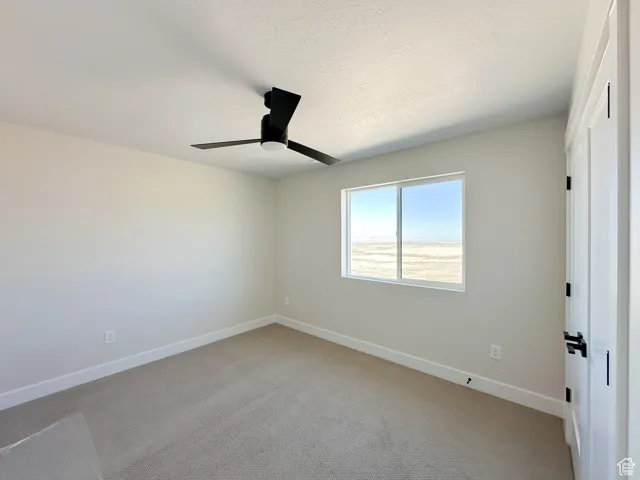 Unfurnished bedroom with baseboards, a textured ceiling, ceiling fan, and light carpet