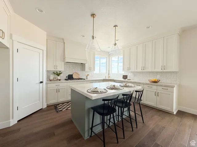 Kitchen with white cabinetry, pendant lighting, a kitchen breakfast bar, dark wood-style flooring, and a textured ceiling