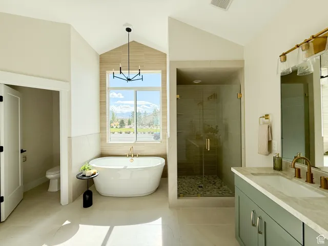 Bathroom with vanity, a freestanding tub, a shower stall, lofted ceiling, and light tile patterned flooring
