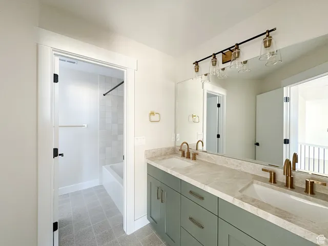 Full bath with baseboards, shower / bathing tub combination, double vanity, and a sink