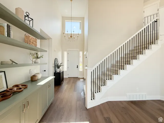 Foyer featuring dark wood-style flooring, a towering ceiling, stairway, and a chandelier