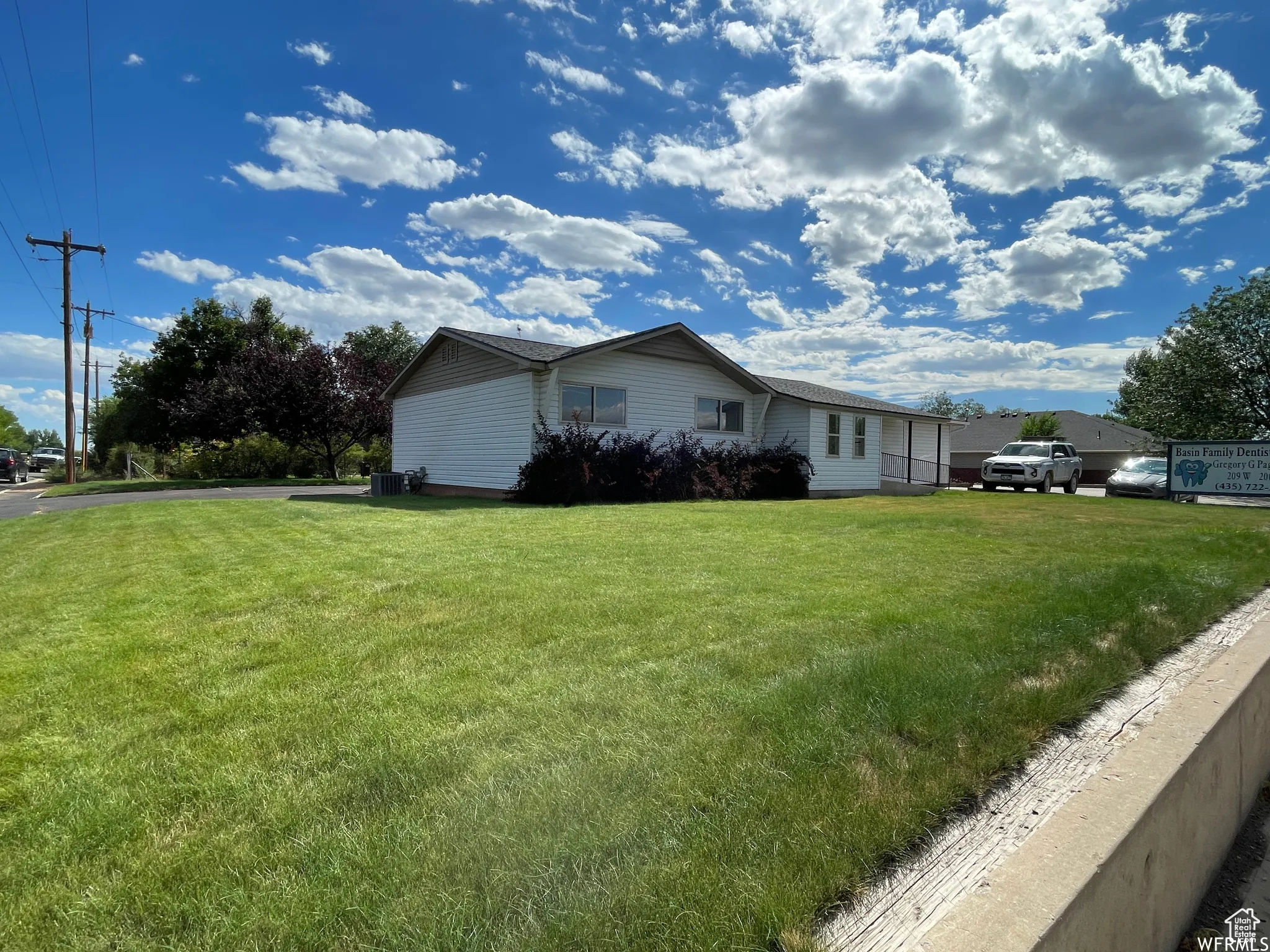 View of side of home featuring cooling unit and a yard