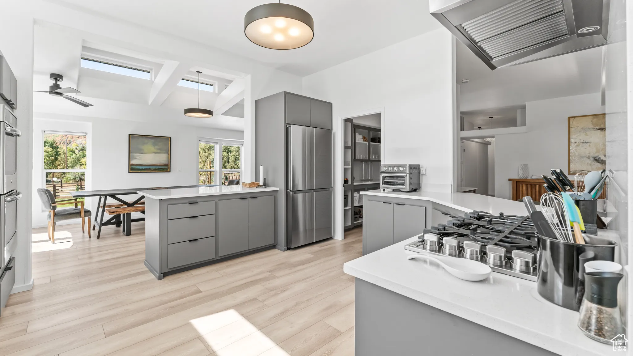 Kitchen with gray cabinets, light countertops, freestanding refrigerator, and light wood-style floors