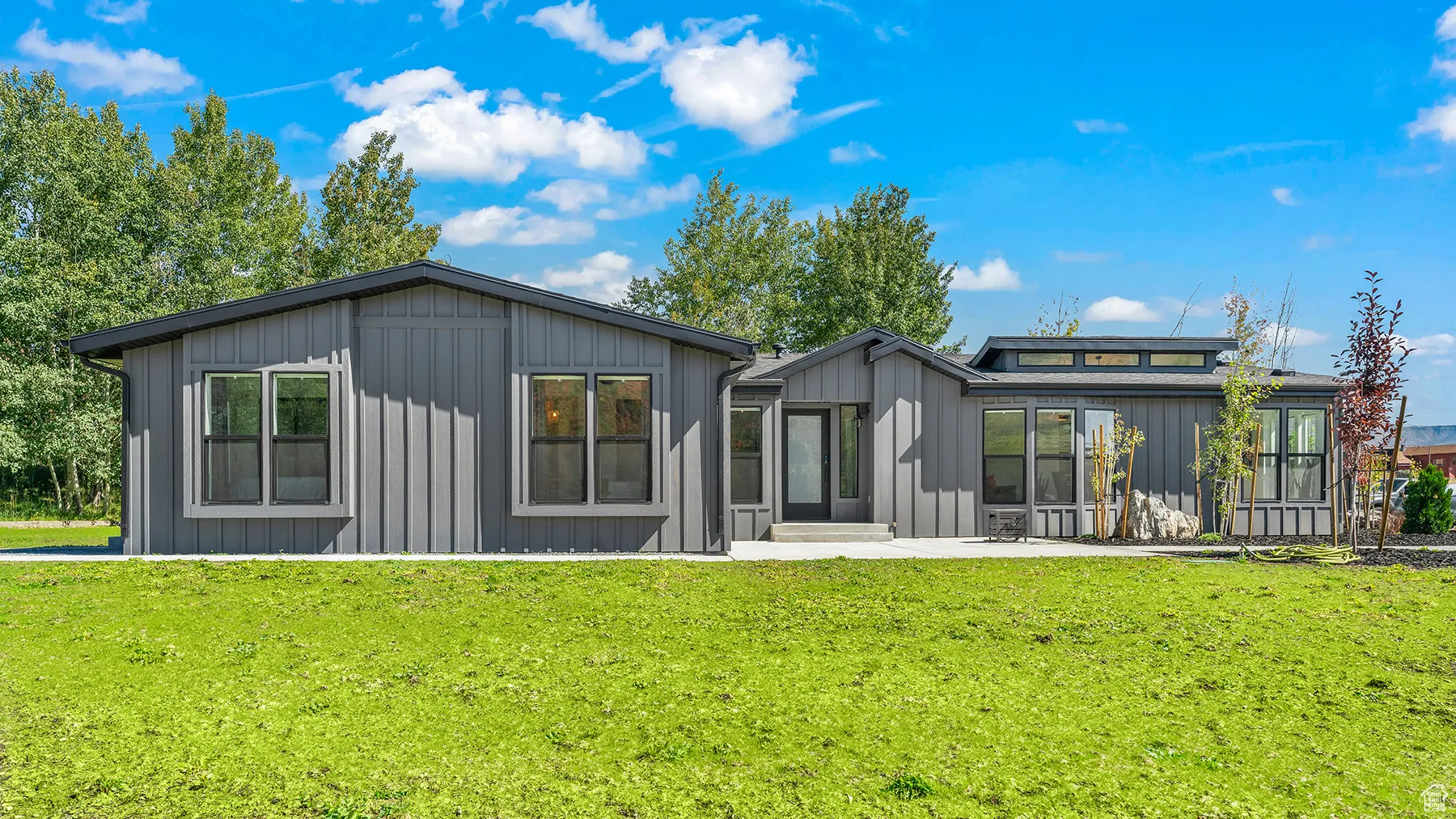 Back of house with a patio, a yard, and board and batten siding