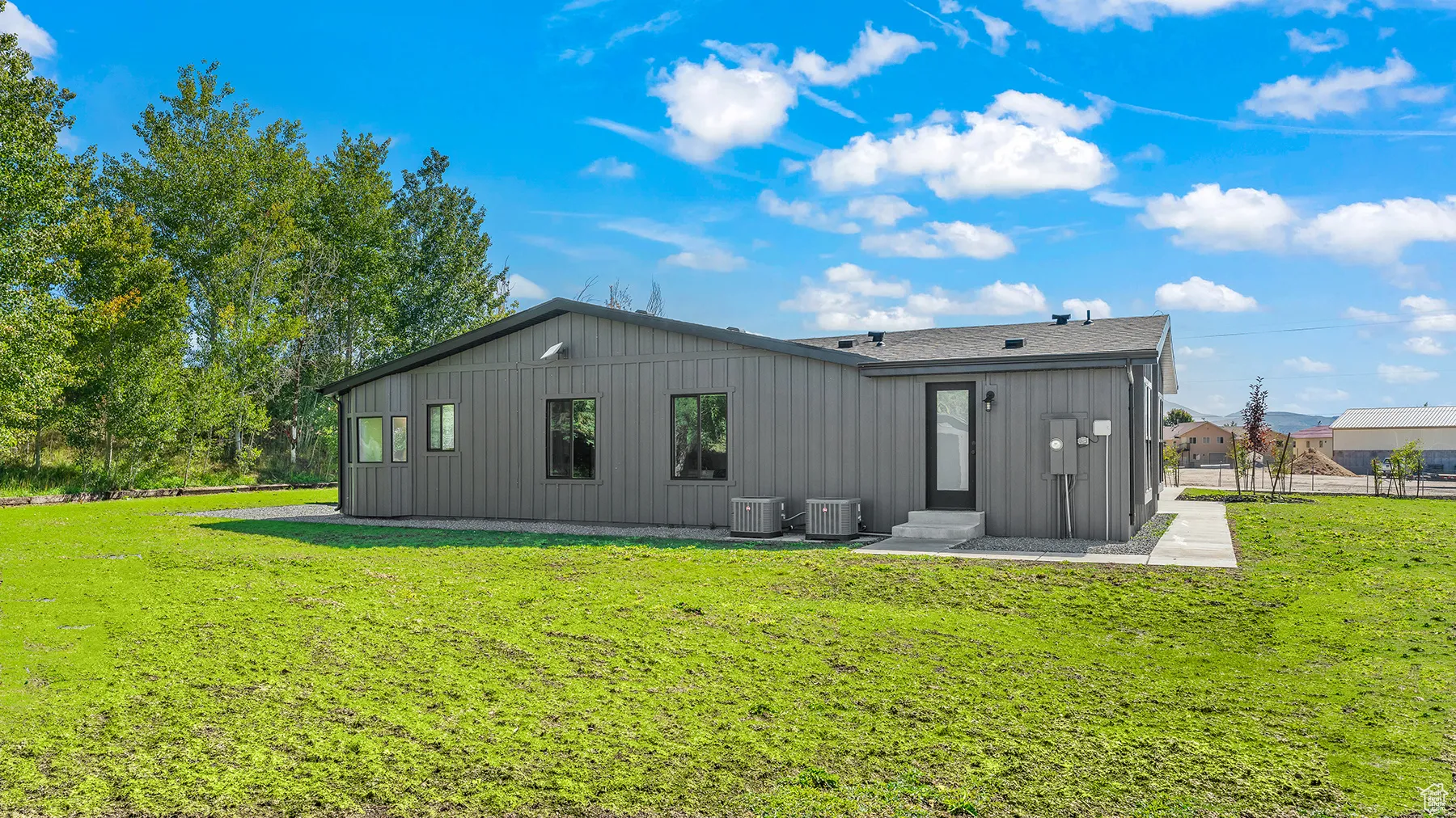 Rear view of property featuring central air condition unit, a yard, board and batten siding, and a shingled roof