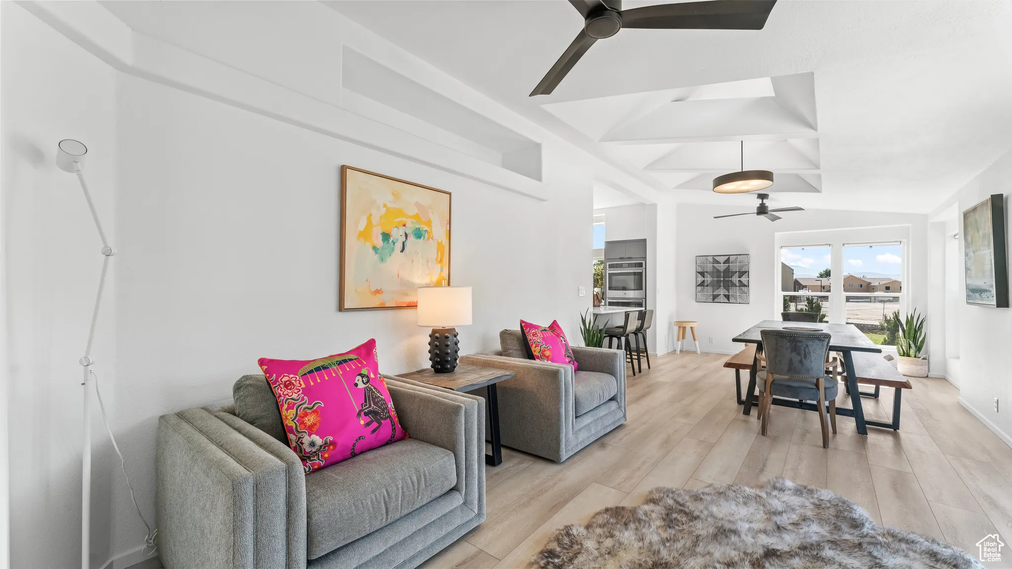 Living area featuring light wood finished floors, baseboards, lofted ceiling, and ceiling fan