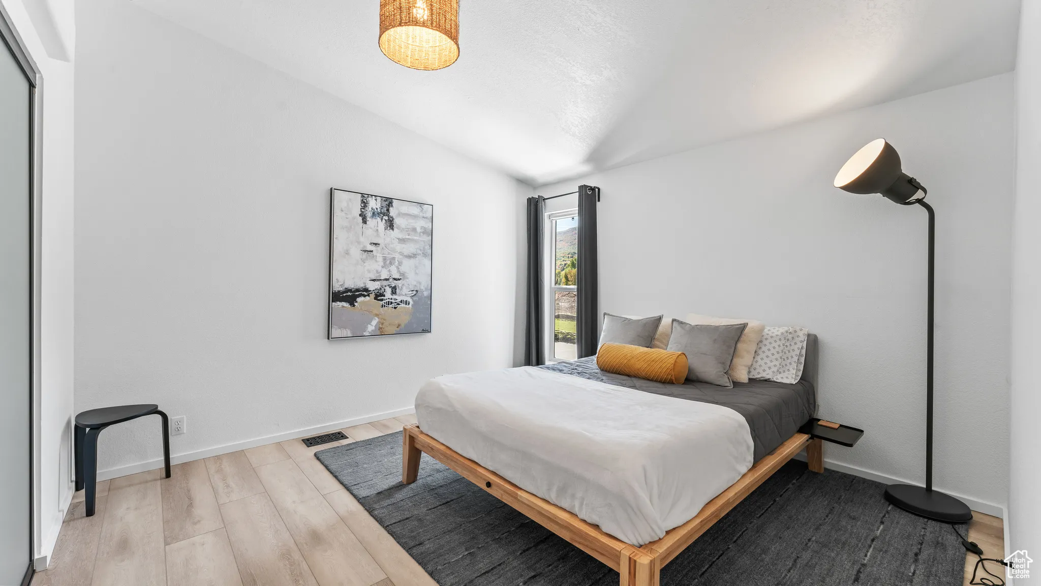Bedroom featuring light wood-type flooring, visible vents, lofted ceiling, and baseboards