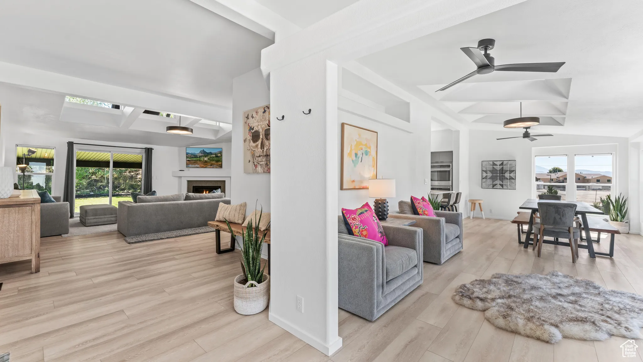 Living room with a warm lit fireplace, a ceiling fan, baseboards, and wood finished floors