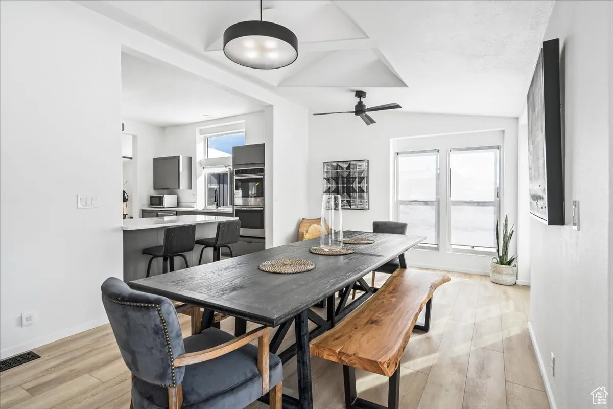 Dining space with vaulted ceiling, visible vents, a wealth of natural light, and light wood-type flooring