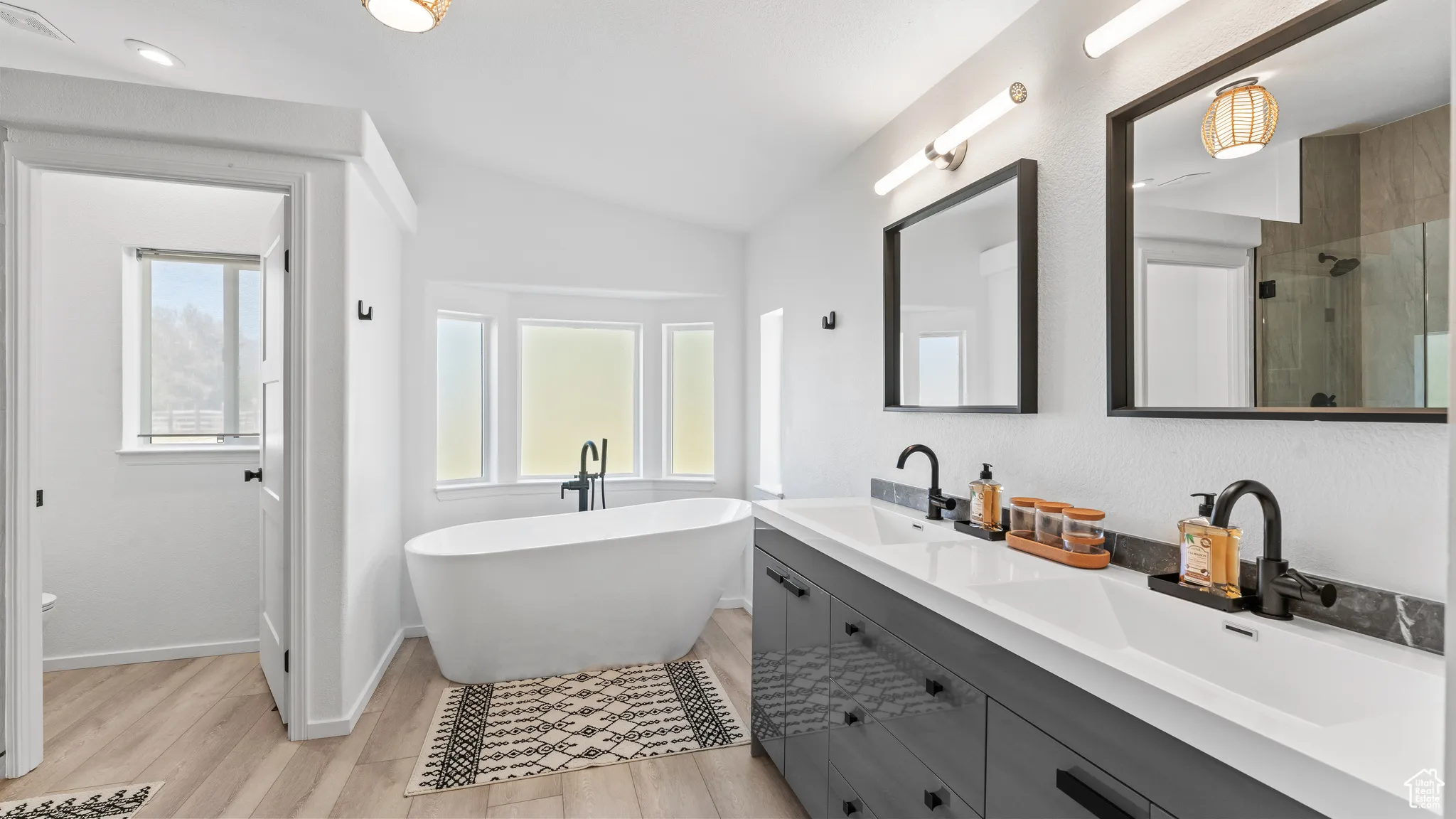 Bathroom with lofted ceiling, wood finished floors, a stall shower, and a sink