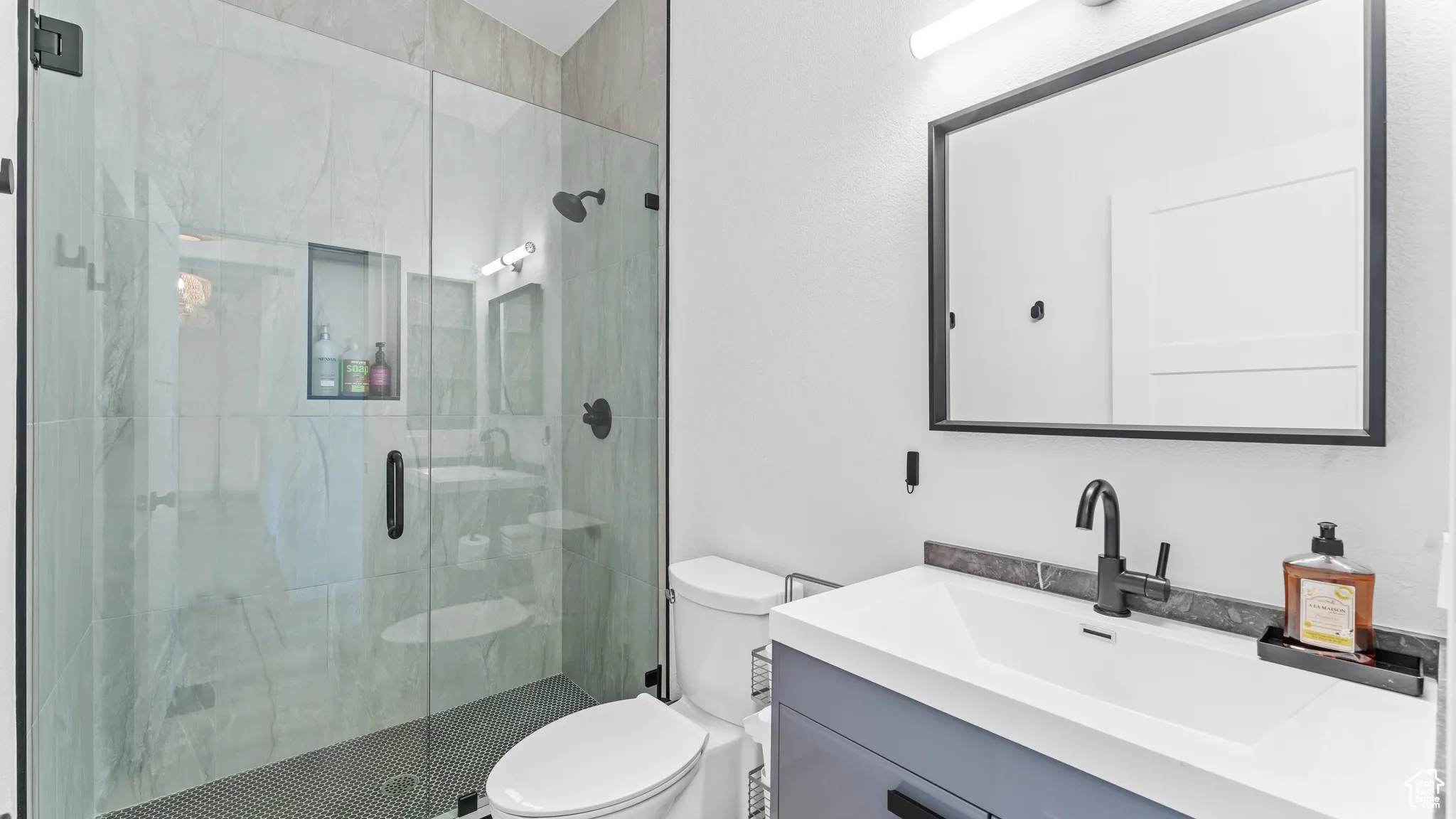 Bathroom featuring a stall shower, toilet, and vanity