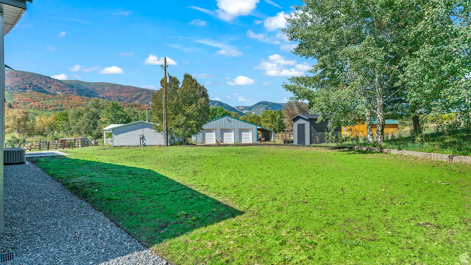 View of yard with a storage shed, an outdoor structure, a mountain view, and central AC