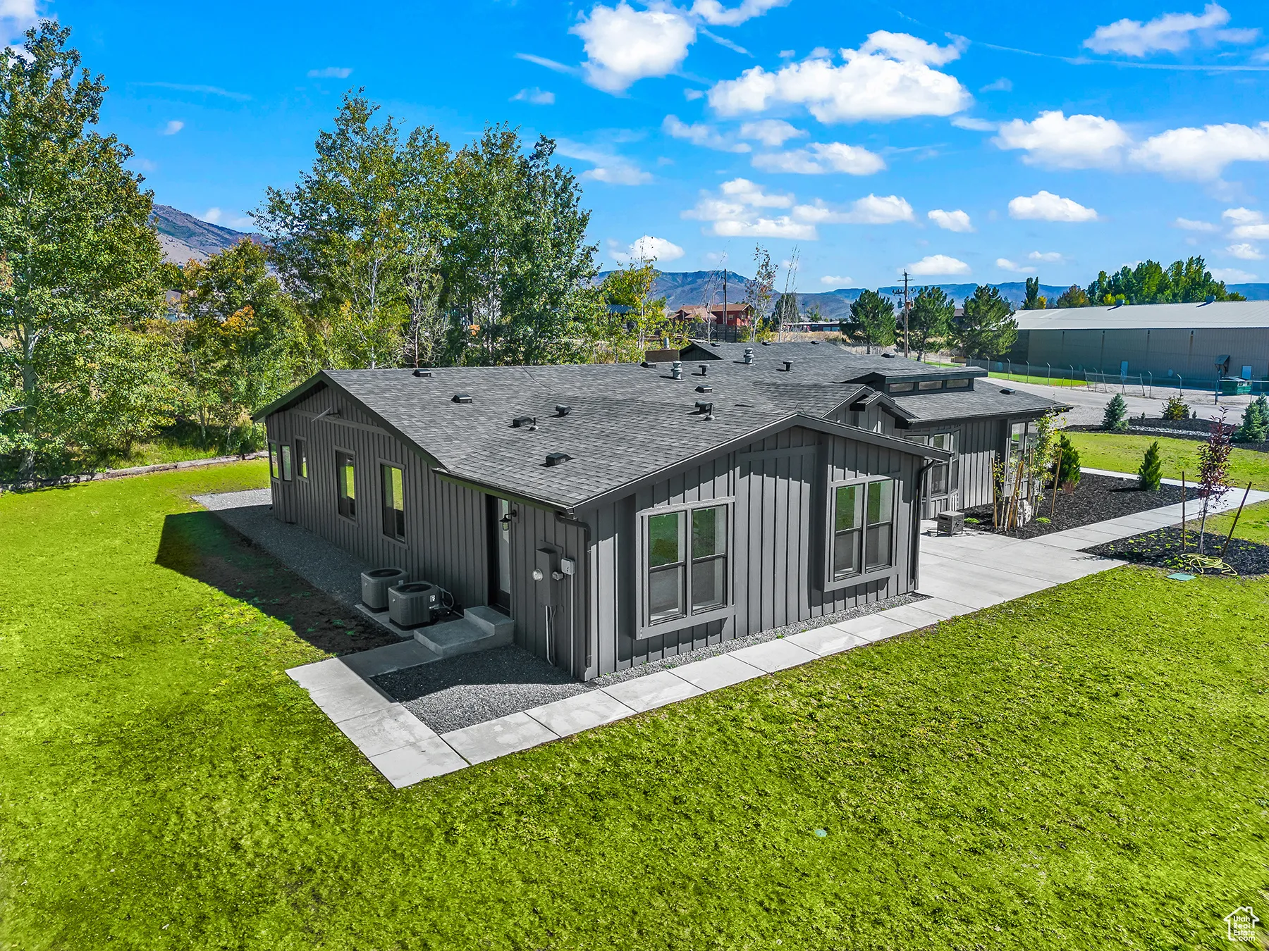 Rear view of house with board and batten siding, a shingled roof, central AC, a lawn, and a mountain view
