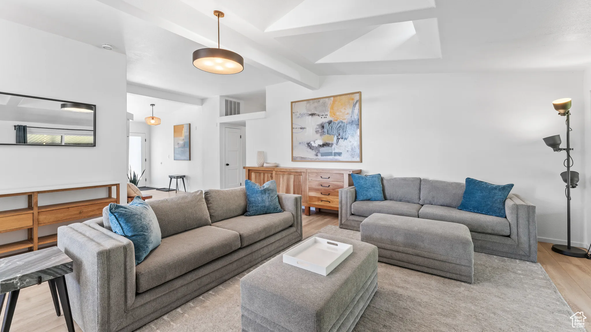 Living area with lofted ceiling with beams, visible vents, and light wood-style floors