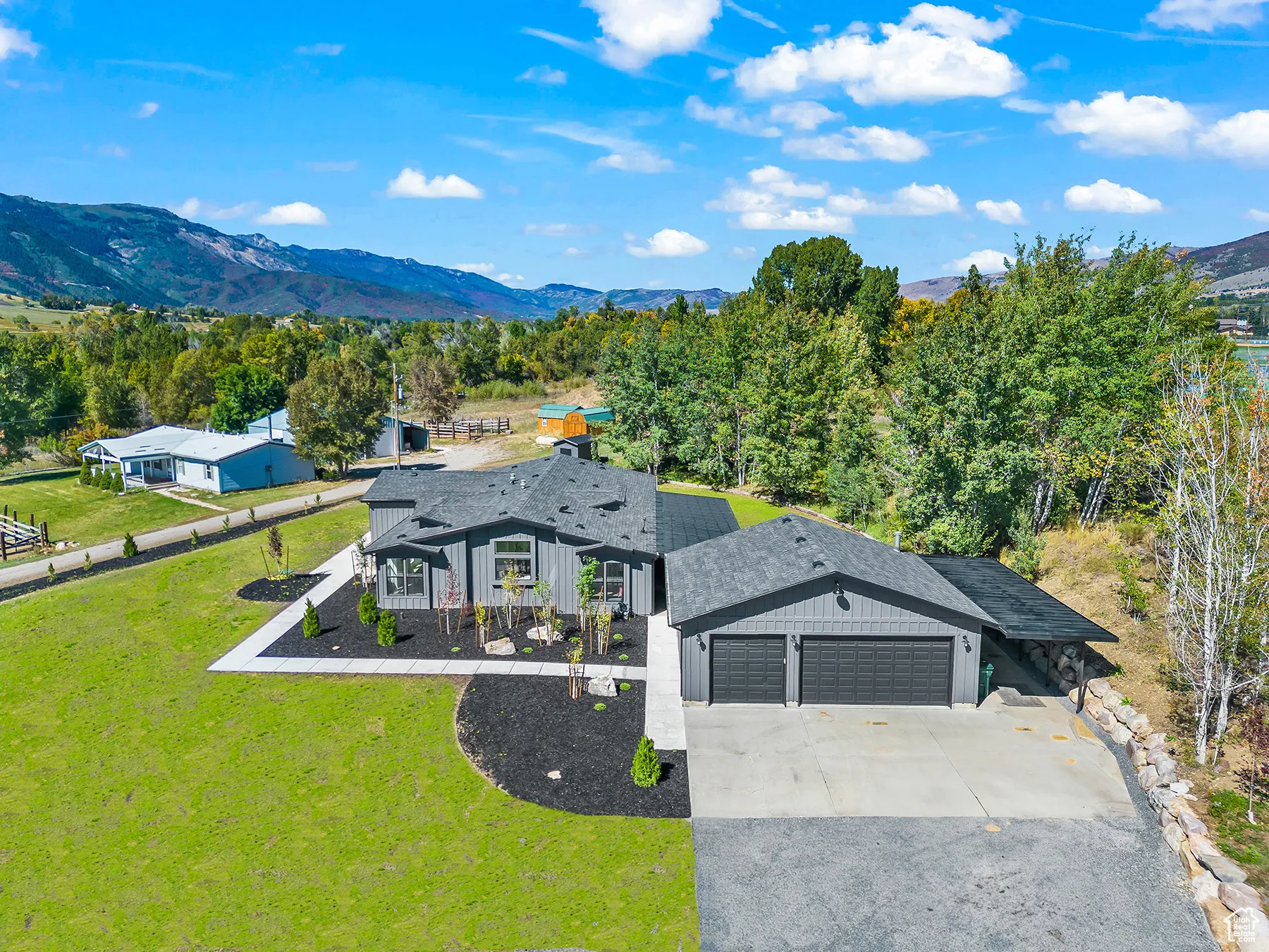 View of front of house with a shingled roof, concrete driveway, a front yard, a garage, and a mountain view