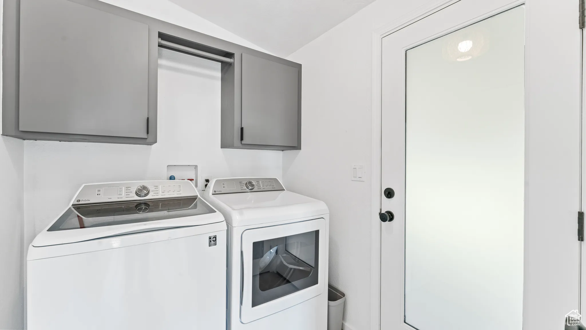 Clothes washing area featuring cabinet space and washing machine and dryer