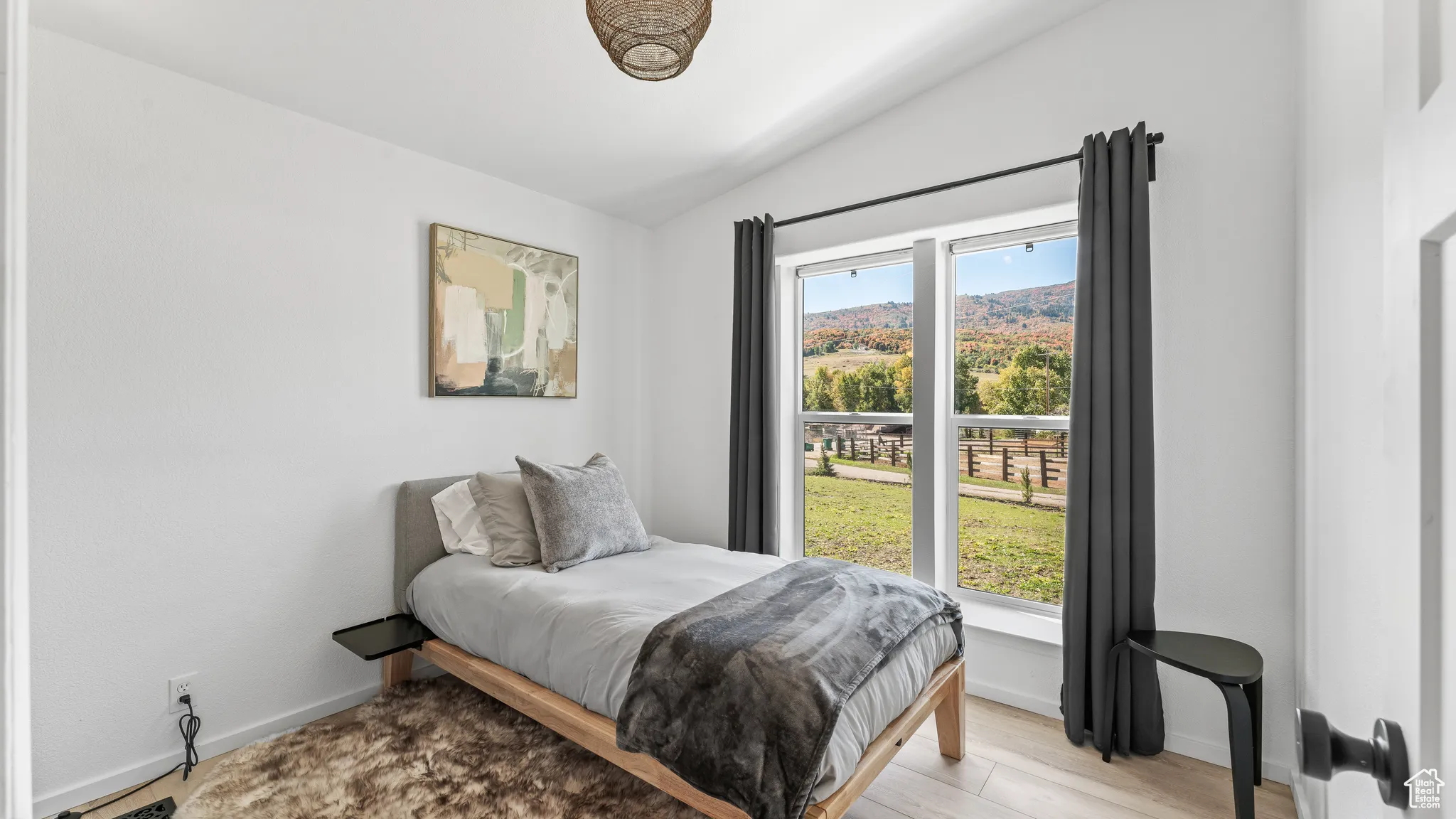 Bedroom featuring lofted ceiling, baseboards, and light wood-type flooring