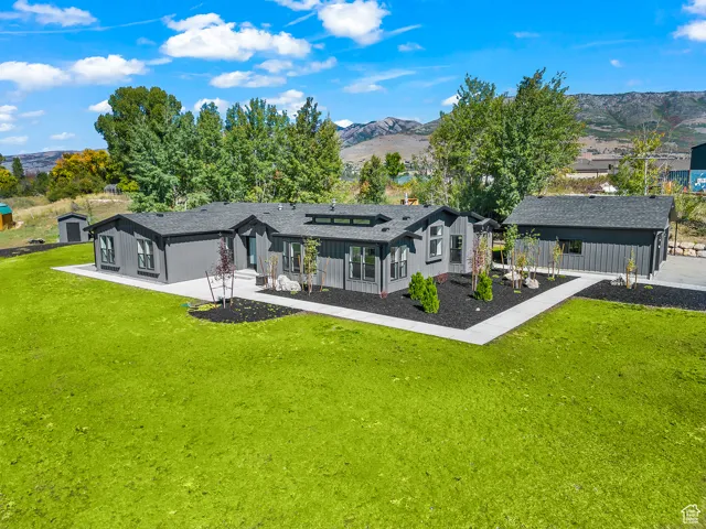 Rear view of property with a lawn, a mountain view, board and batten siding, an outdoor structure, and roof with shingles