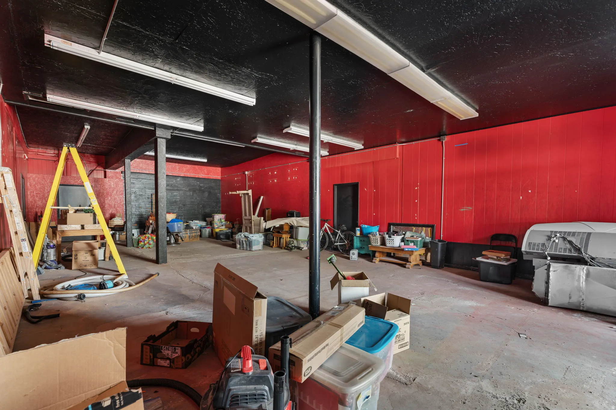 This image shows an unfinished or under-renovation commercial or industrial space with exposed structural elements, construction materials, and equipment present throughout