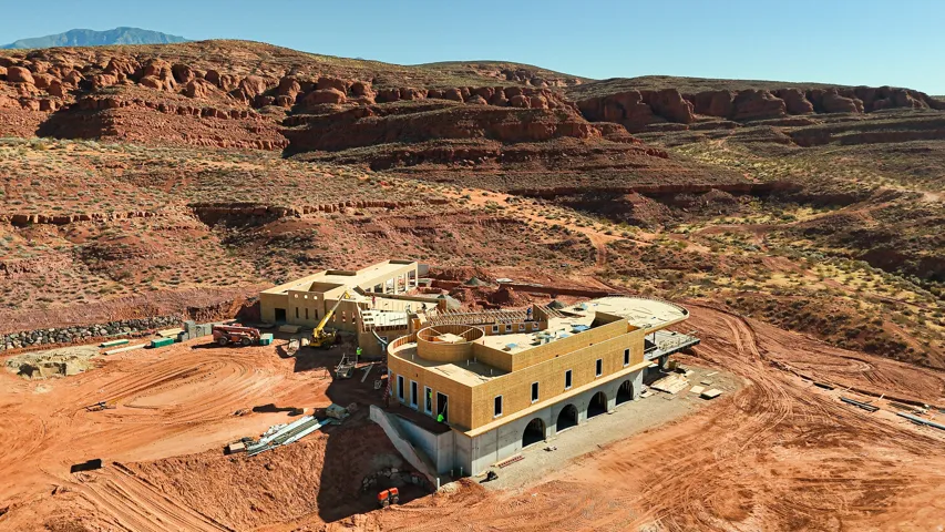 Expansive property featuring multiple structures under construction, set against a rugged mountain backdrop
