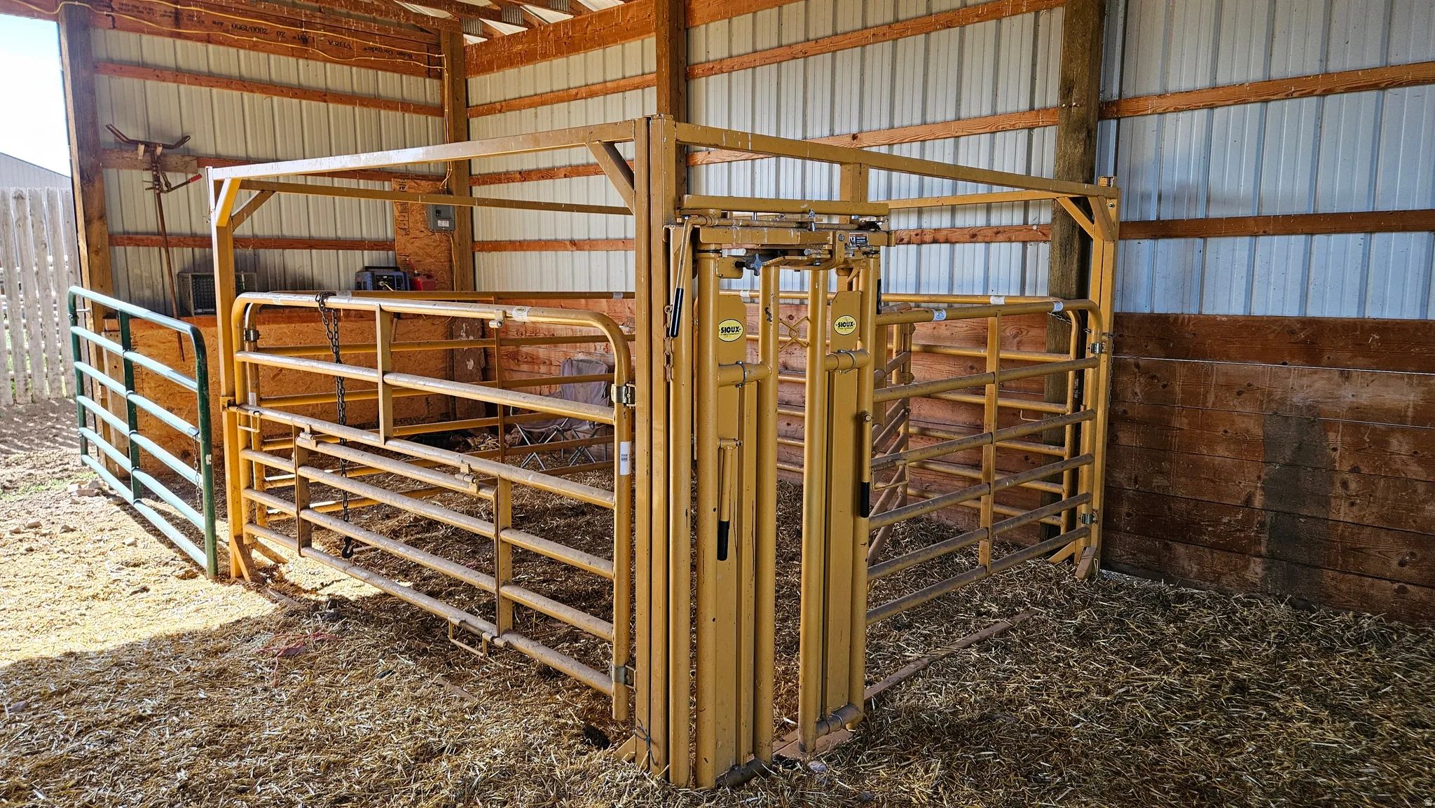 Open-sided barn structure featuring wood posts, metal siding, and a slatted wood wall