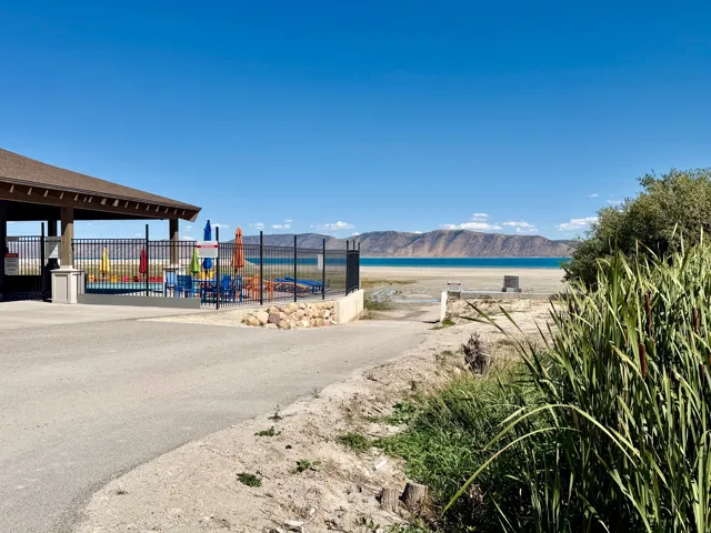 Covered outdoor recreation area with fenced pool, paved access, and natural landscaping