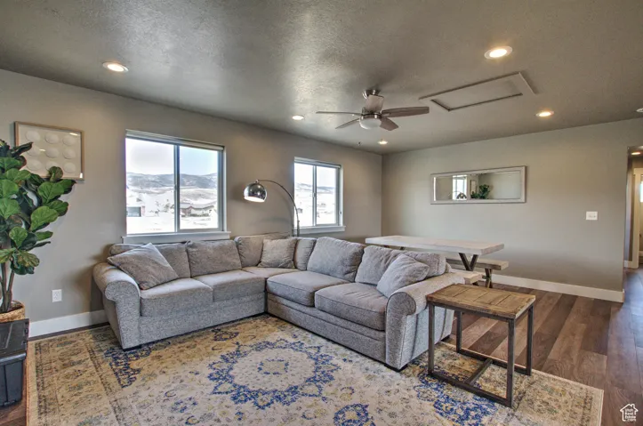 Living area with recessed lighting, baseboards, attic access, and wood finished floors