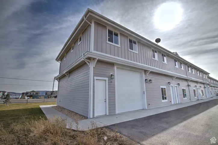 Exterior space with a lawn, board and batten siding, driveway, and a garage