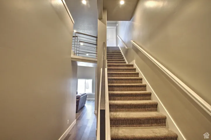 Stairs featuring a high ceiling, baseboards, and wood finished floors