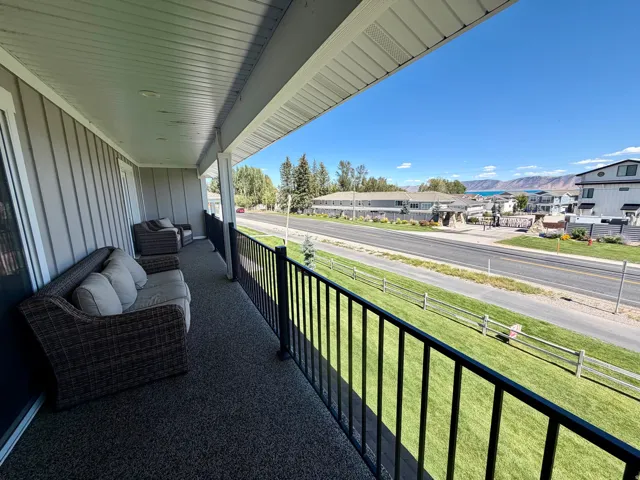 Expansive covered balcony featuring a black metal railing and a textured floor