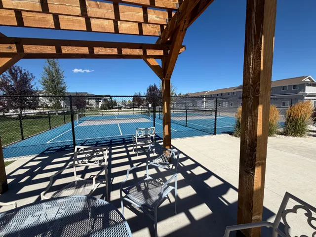 Pickleball court. Wood pergola structure over concrete patio, adjacent to fenced outdoor courts