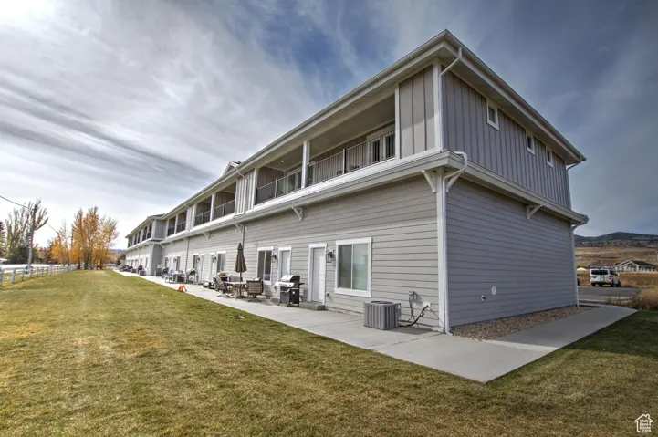 Patio located on the back of  the units featuring a yard, a patio area, board and batten siding, and cooling unit