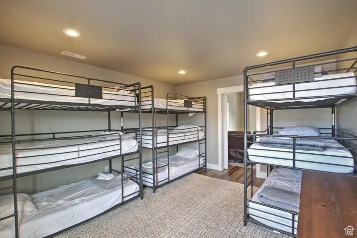 Bedroom with wood finished floors, recessed lighting, visible vents, and baseboards