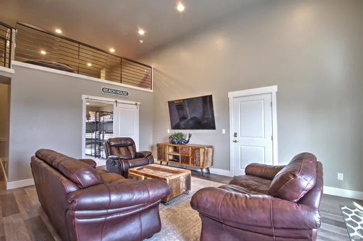 Living area with a high ceiling, recessed lighting, wood finished floors, and baseboards