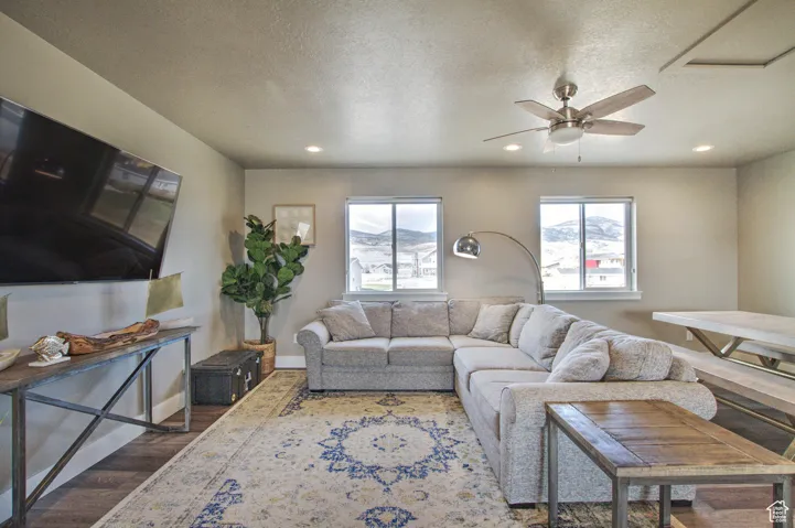 Living room with baseboards, recessed lighting, wood finished floors, a textured ceiling, and a ceiling fan
