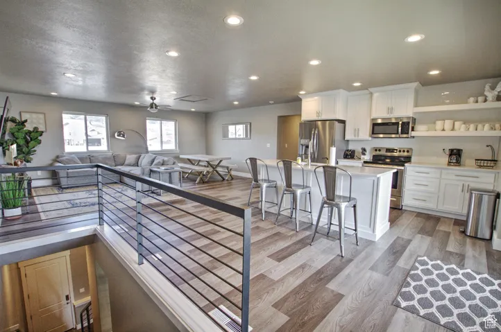 Kitchen with light wood finished floors, open floor plan, light countertops, appliances with stainless steel finishes, and white cabinets