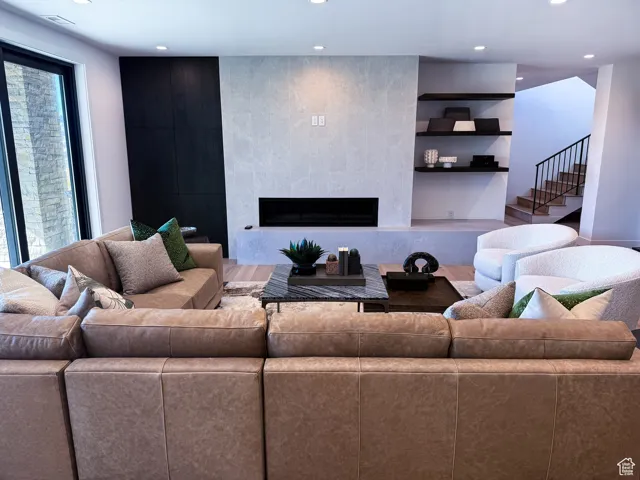 Living room with a tiled fireplace, recessed lighting, stairs, and built in features