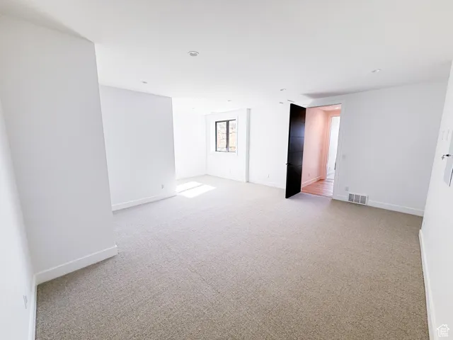 Unfurnished room featuring light carpet and baseboards