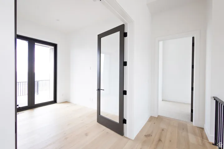 Corridor featuring french doors, light wood finished floors, and baseboards