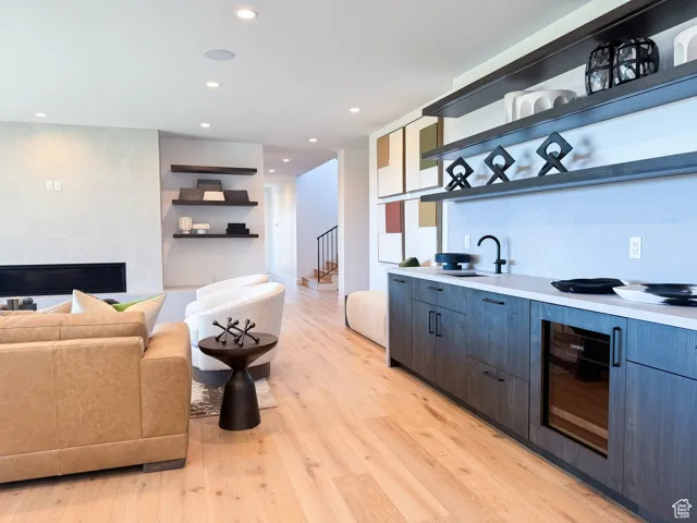 Bar area with open shelves, a large fireplace, modern cabinets, light countertops, and light wood-type flooring