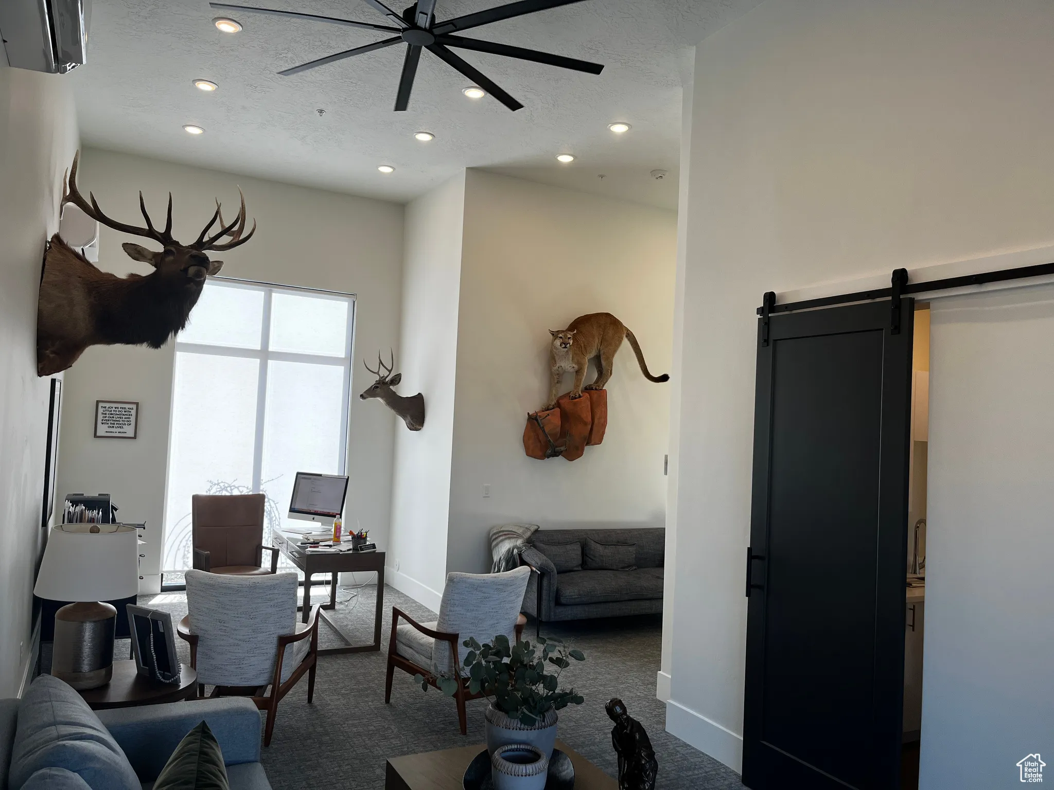 Living room with carpet, a ceiling fan, a barn door, a textured ceiling, and recessed lighting