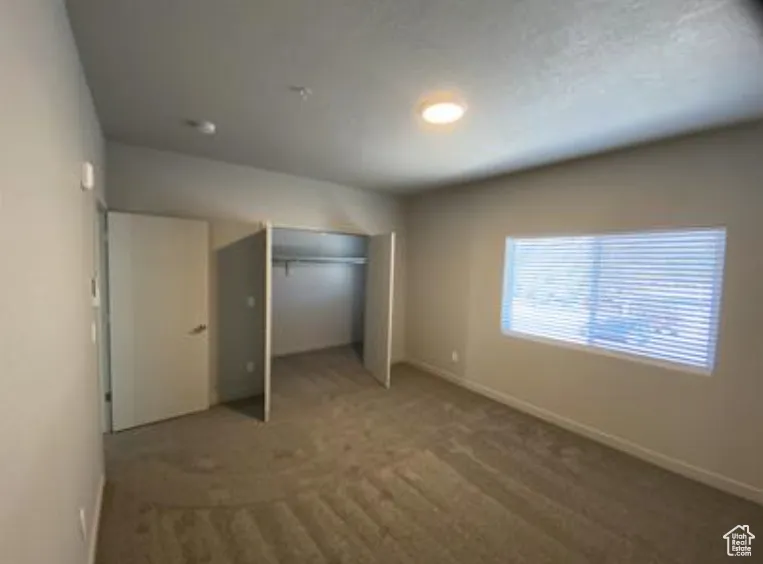 Unfurnished bedroom with a closet, carpet flooring, and baseboards