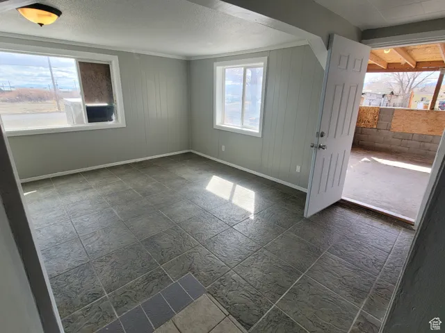 Empty room featuring plenty of natural light, a textured ceiling, and baseboards